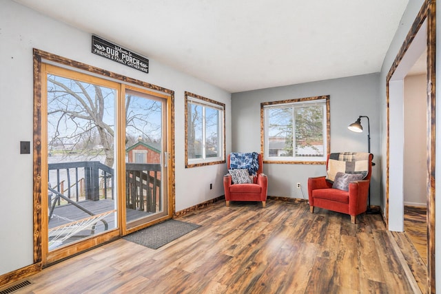 living area featuring wood finished floors, visible vents, and baseboards