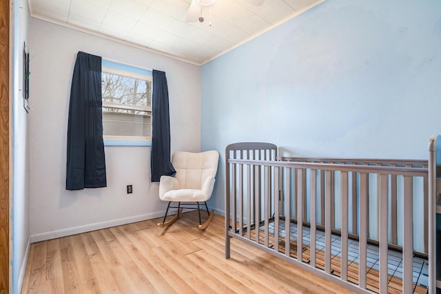 bedroom featuring wood finished floors, crown molding, and baseboards