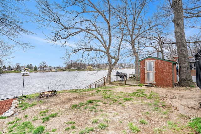 view of yard with fence, an outdoor structure, a storage shed, and a water view