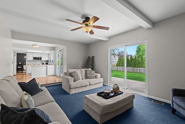 living room with a ceiling fan, baseboards, visible vents, light carpet, and beam ceiling