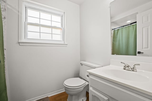 bathroom with toilet, wood finished floors, vanity, curtained shower, and baseboards