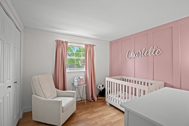 bedroom featuring light wood finished floors, a nursery area, and a closet