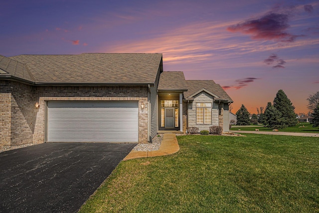 single story home featuring driveway, an attached garage, a yard, brick siding, and roof with shingles