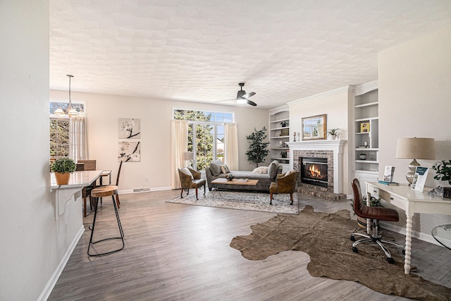 living room featuring baseboards, a brick fireplace, wood finished floors, and a wealth of natural light