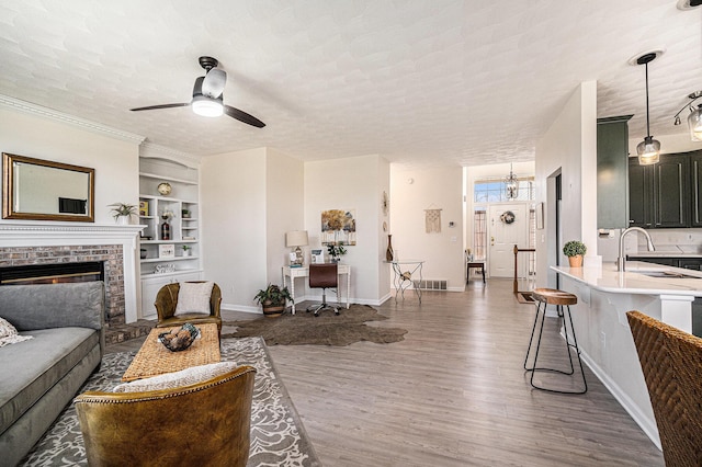 living area featuring baseboards, wood finished floors, built in features, and ceiling fan