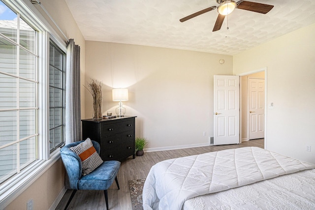 bedroom with baseboards, a ceiling fan, wood finished floors, and multiple windows