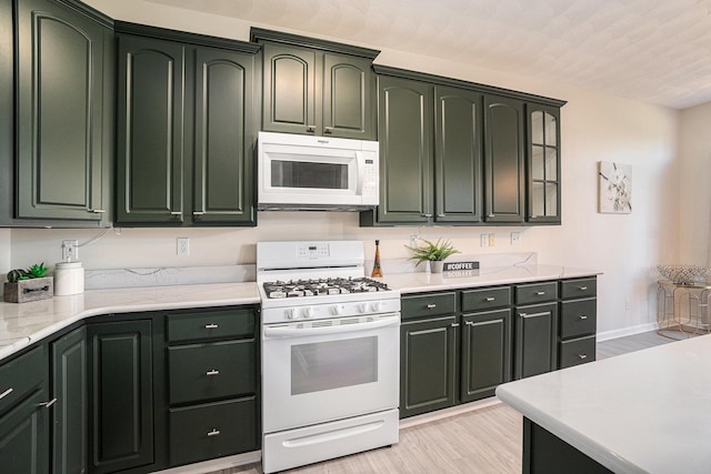 kitchen with green cabinetry, light wood-style floors, and white appliances