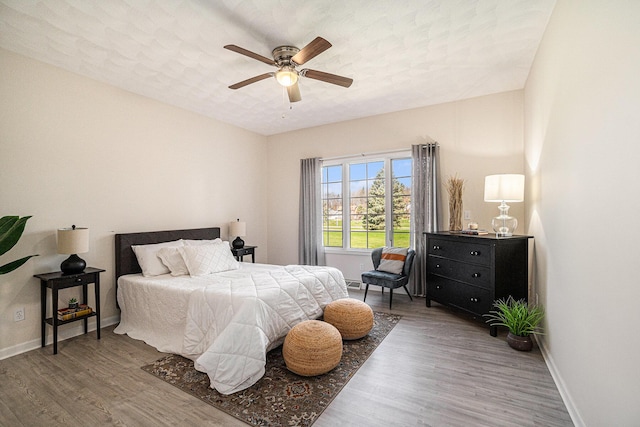 bedroom with wood finished floors, a ceiling fan, and baseboards
