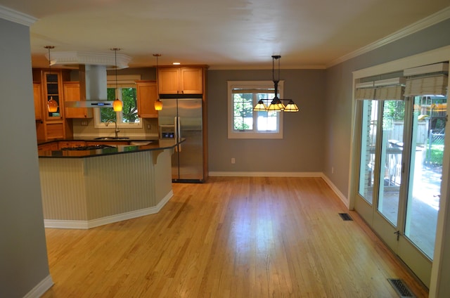 3629 Frederick Dr, Ann Arbor, MI 48105 - kitchen with stainless steel fridge, wall chimney range hood, dark countertops, healthy amount of natural light, and ornamental molding