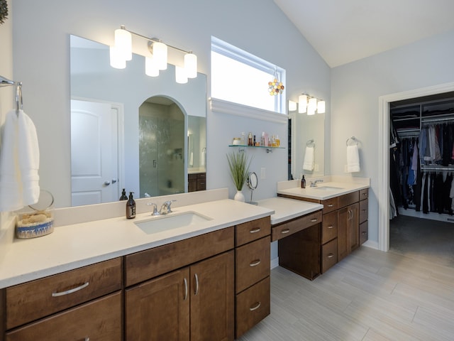 full bath featuring two vanities, lofted ceiling, a stall shower, and a sink