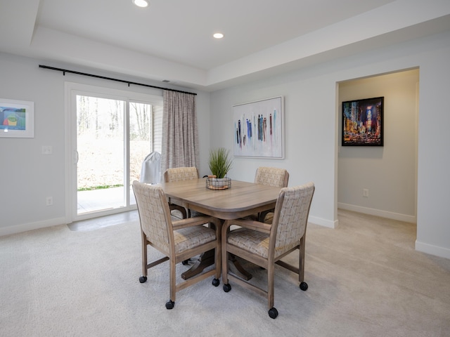 dining space featuring light colored carpet, baseboards, a tray ceiling, and recessed lighting