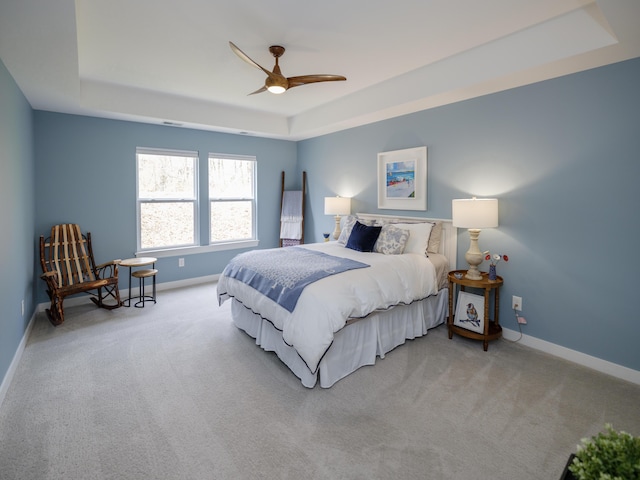 carpeted bedroom with baseboards, a ceiling fan, and a raised ceiling