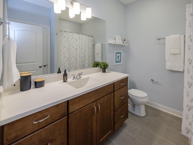 bathroom with baseboards, toilet, and vanity