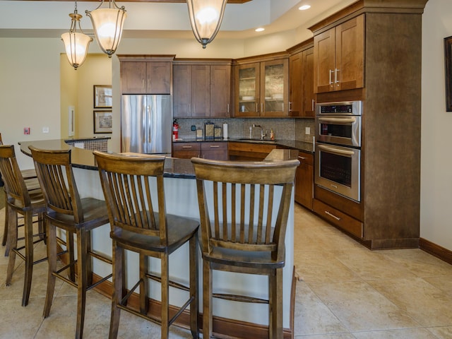 kitchen featuring a sink, a kitchen island, decorative backsplash, glass insert cabinets, and appliances with stainless steel finishes