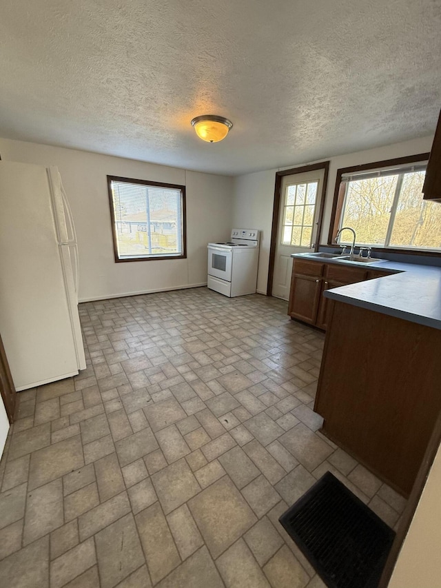 interior space featuring baseboards, white appliances, brick patterned floor, and a sink