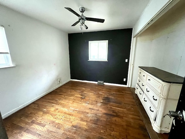 empty room featuring baseboards, dark wood-style floors, and ceiling fan