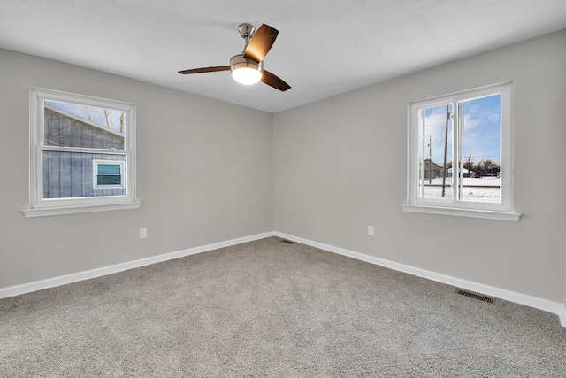 empty room featuring a wealth of natural light, baseboards, visible vents, and carpet