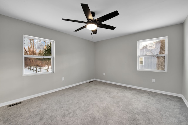 spare room with baseboards, a ceiling fan, visible vents, and a healthy amount of sunlight