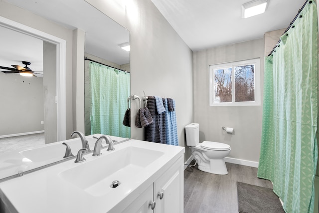 bathroom featuring a ceiling fan, wood finished floors, vanity, baseboards, and toilet