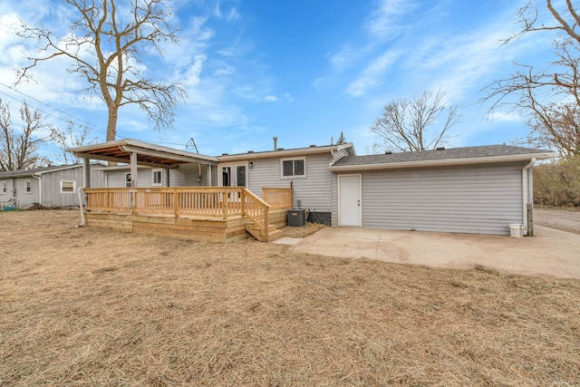 back of property with a wooden deck, a yard, central AC, and a patio