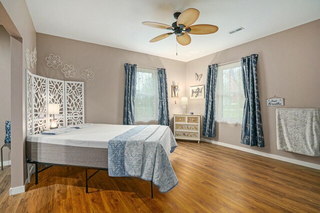 bedroom with visible vents, baseboards, wood finished floors, and ceiling fan