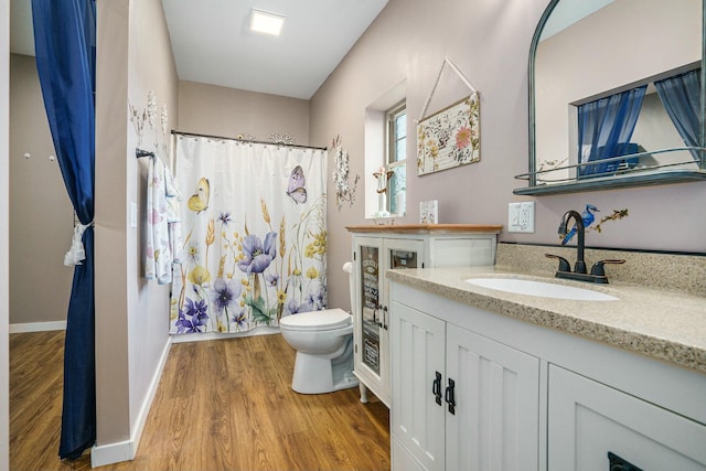 bathroom with wood finished floors, curtained shower, vanity, and toilet