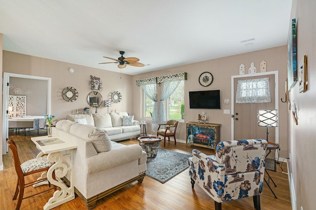 living room with wood finished floors, baseboards, and ceiling fan