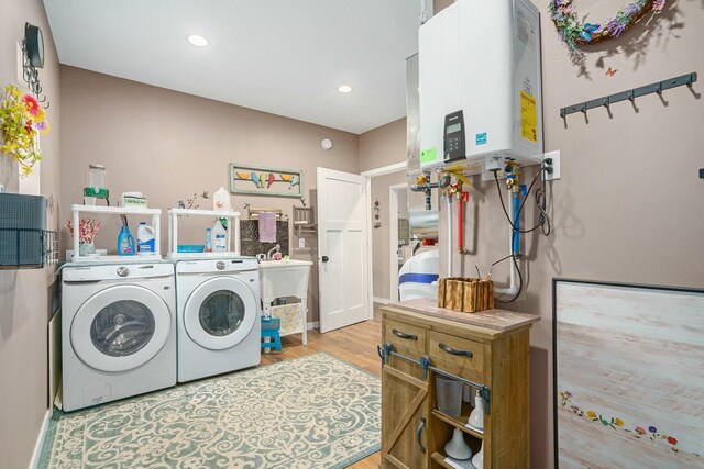 laundry area featuring light wood-type flooring, washer and dryer, tankless water heater, laundry area, and recessed lighting