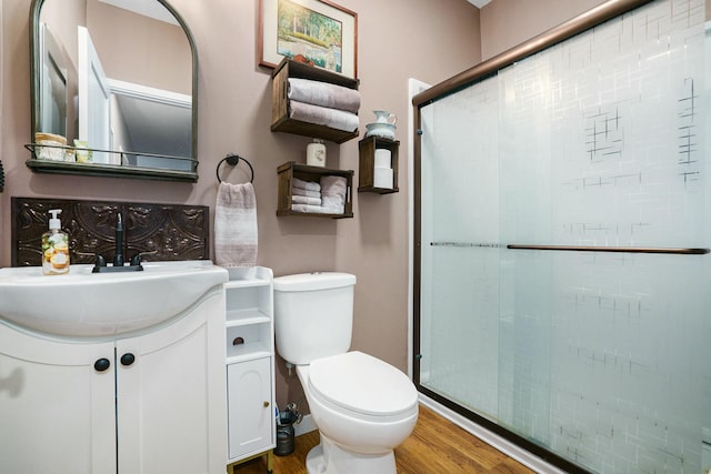 full bath featuring wood finished floors, vanity, toilet, and a stall shower
