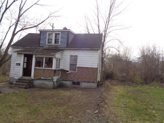bungalow-style home featuring a chimney, a shingled roof, entry steps, and a front yard
