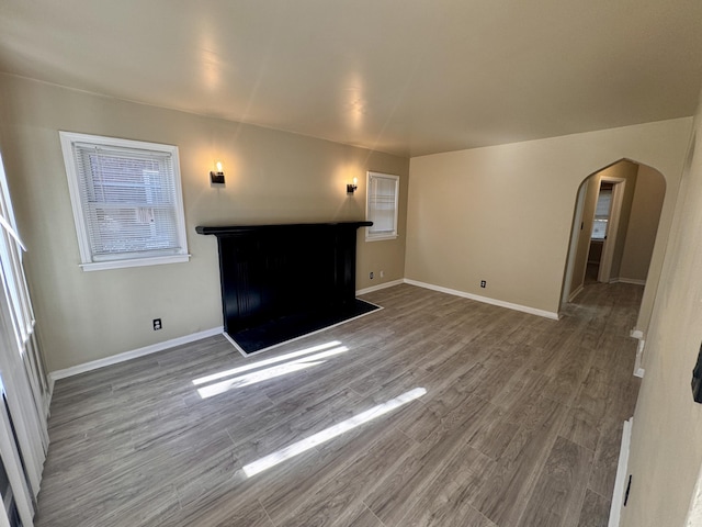 15241 Seymour St, Detroit, MI 48205 - unfurnished living room with baseboards, a fireplace, wood finished floors, and arched walkways