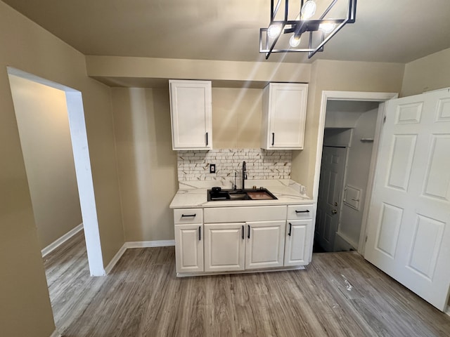 15241 Seymour St, Detroit, MI 48205 - kitchen with white cabinets, a sink, light wood-type flooring, decorative backsplash, and light countertops