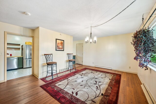 1843 N Sierra Way, Stevensville, MI 49127 - dining area featuring wood finished floors, a notable chandelier, and a baseboard radiator