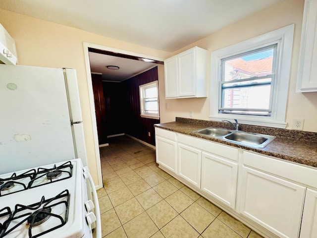 kitchen featuring dark countertops, white appliances, a sink, and light tile patterned floors