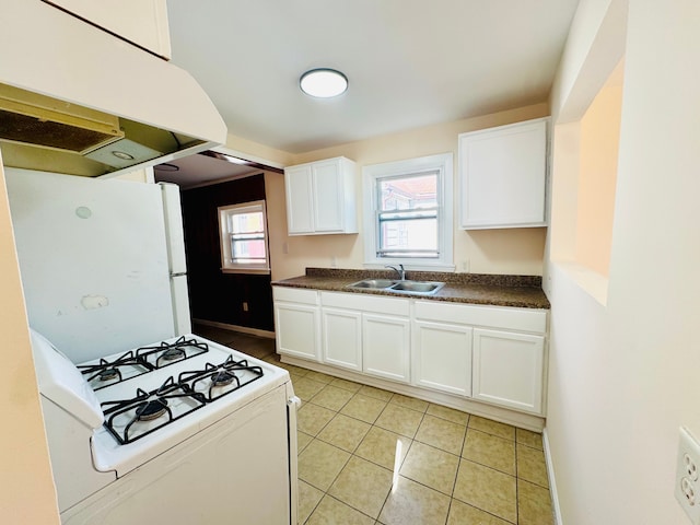 kitchen with dark countertops, a sink, white appliances, white cabinets, and under cabinet range hood