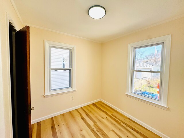 spare room featuring baseboards, ornamental molding, and light wood-style flooring