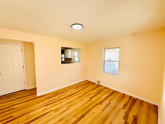 spare room with baseboards, visible vents, and light wood-style flooring
