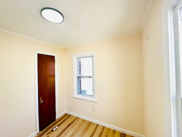 empty room with light wood-type flooring, crown molding, and baseboards
