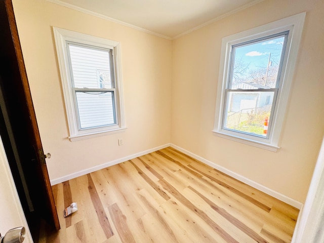 unfurnished room featuring light wood-style floors, crown molding, and baseboards