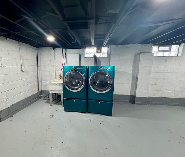 below grade area featuring washing machine and clothes dryer and a sink