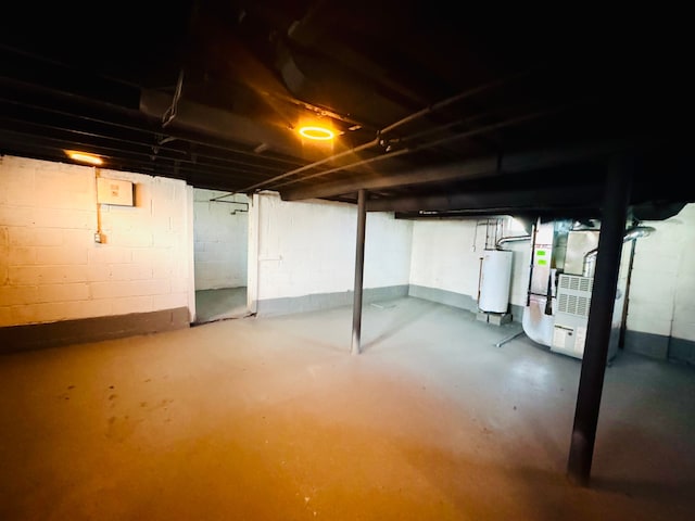 unfinished below grade area featuring concrete block wall, heating unit, and water heater