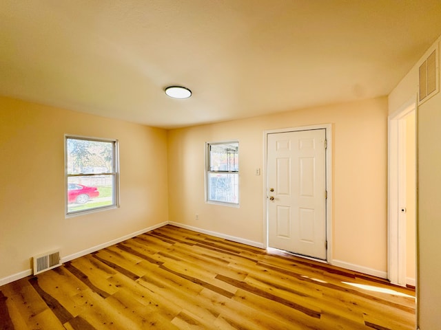 unfurnished room with plenty of natural light, light wood-style flooring, visible vents, and baseboards