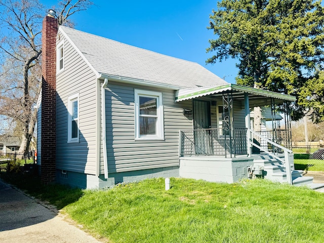 bungalow featuring a shingled roof, a chimney, and a front yard