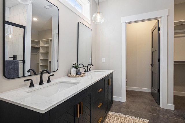 full bathroom featuring a spacious closet, concrete flooring, a sink, and baseboards
