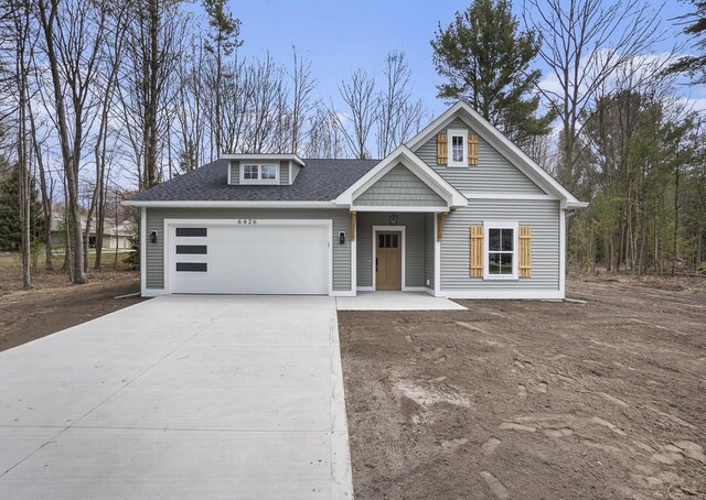 view of front of house featuring a garage, driveway, and roof with shingles