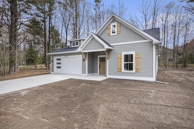 view of front of house featuring a garage, driveway, and roof with shingles