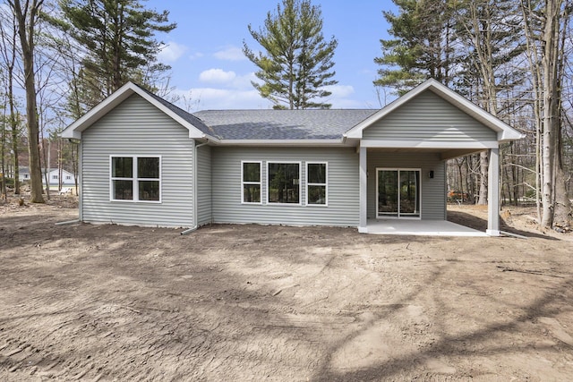 rear view of property featuring a shingled roof and a patio