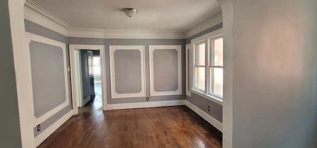 spare room with crown molding, baseboards, dark wood-style flooring, and a healthy amount of sunlight