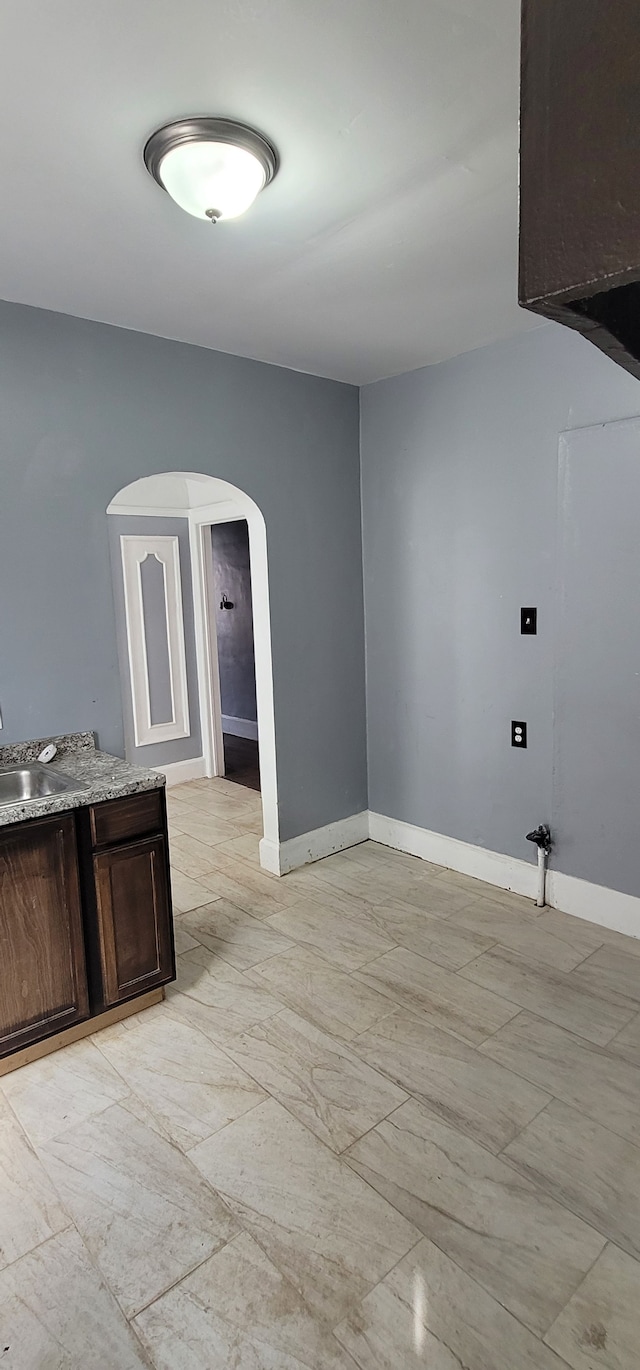 interior space with arched walkways, baseboards, and a sink