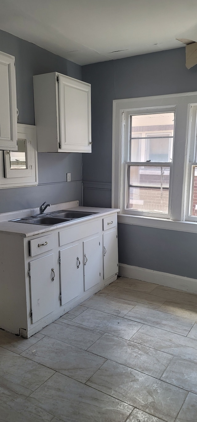 kitchen featuring light countertops, a sink, and white cabinetry